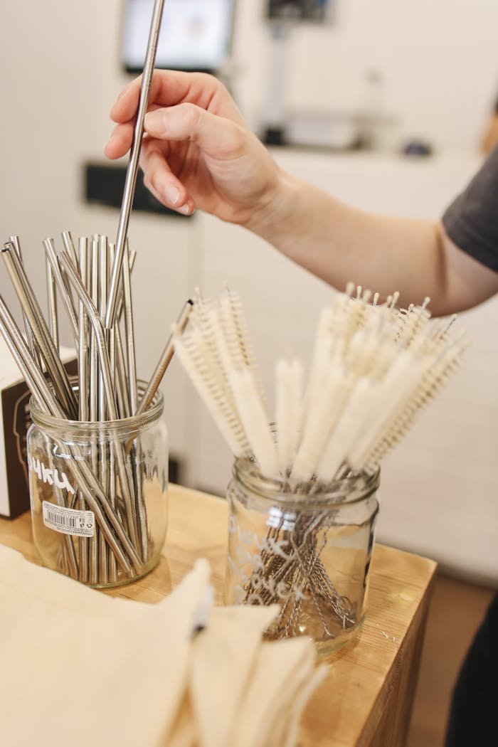 Person selecting metal straws in a zero waste shop with focus on sustainability.
