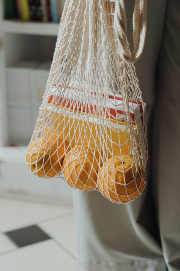 Close-up of oranges in a reusable string bag, perfect for eco-friendly shopping.